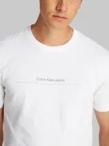 Remera blanca de algodón con cuello redondo y mangas cortas. Presenta un estampado en relieve de Calvin Klein Jeans en el pecho.