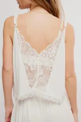 Conjunto de dos piezas de color blanco, confeccionado en viscosa fluida y liviana. Incluye una musculosa con escote en V, detalles de encaje y tirantes finos regulables, y un short con cintura elastizada y bordes de puntilla.