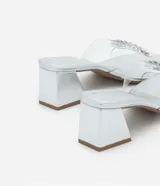 Sandalia mule con puntera cuadrada, capellada de vinilo transparente con aplique de pedrería plateada y tacón bloque plateado.