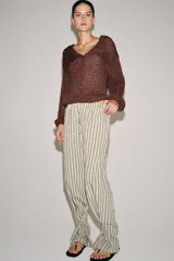 Pantalón de tiro medio con diseño de rayas verticales, confeccionado en mezcla de viscosa. Presenta cintura elástica ajustable con cordones, bolsillos laterales ocultos y pierna recta con bajo ajustable mediante botón.