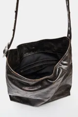 Bolso de hombro formato shopper con acabado efecto cuero desgastado. Cuenta con asa ajustable mediante hebilla metálica y detalle de tachas, cierre principal mediante imán y bolsillo interior con cremallera.