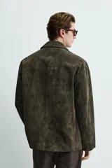Blazer de corte relajado confeccionada en piel con acabado de ante. Presenta cuello con solapas de muesca, cierre frontal de tres botones y bolsillos de doble vivo en la cadera.