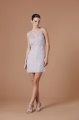 Vestido corto negro de tirantes, con escote en V y tejido translúcido con brillos y flecos.