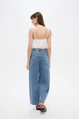 Pantalón jean slouchy de tiro alto, color natural, con detalle de bordadoado en el borde inferior.