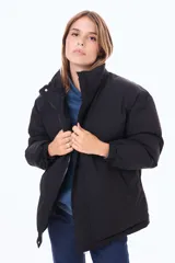 Campera puffer de corte holgado, color negro, con cuello alto, cierre frontal y puños elásticos.