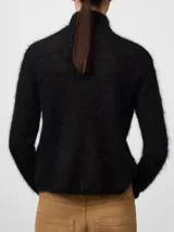 Sweater de punto cardado con textura suave y esponjosa, cuello chimenea y manga larga. Presenta un diseño minimalista y elegante con etiqueta logotipada en la espalda.