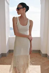 Vestido midi de escote redondo y sin mangas, confeccionado en tejido con textura. Presenta un diseño recto con bajo acabado en capas de flecos largos al tono.