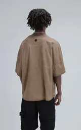 Remera de manga corta con calce extra oversize, color marrón chocolate con efecto gastado/deslavado. Presenta un corte con recortes horizontales en el frente y la espalda, y cuello redondo con terminación deshilachada.