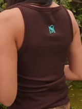 Top de punto acanalado, con diseño ajustado que realza la silueta. Presenta bordados en la parte delantera y trasera, aportando un toque distintivo.