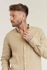 Camisa de corte slim en color beige, confeccionada en tejido de lino, con cuello mao y cierre frontal de botones.