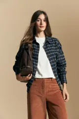 Camisa de estilo leñador con estampado de cuadros en tonos azul, negro y marrón. Presenta cuello clásico, cierre frontal con botones y mangas largas con puños abotonados.