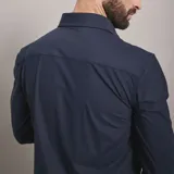 Camisa de vestir negra de manga larga, confeccionada en tejido técnico elástico y libre de arrugas, con cuello clásico y cierre frontal de botones.