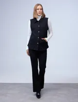 Chaleco negro capitoneado con cuello con solapa, abertura central con botones y bolsillos delanteros.