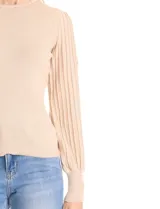 Buzo de tejido lurex en color beige, con cuello redondo y mangas largas con diseño plisado y puños con aplique de botones dorados.