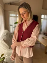 Camisa de color rosado con cuello estilo bebé decorado con puntilla bordada. Presenta mangas largas abullonadas con puños rectos y cierre frontal con botones a tono.