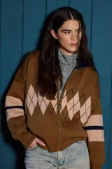 Campera tejida de punto con cierre frontal completo y cuello alto. Presenta un diseño con patrón de rombos en la parte central y franjas horizontales en las mangas.