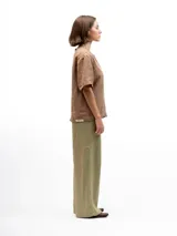 Remera de lino con corte holgado, cuello redondo y mangas cortas. Presenta un diseño minimalista con detalle de botones en la espalda.