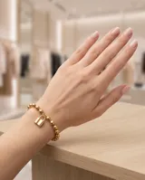 Pulsera de acero italiano con baño de oro, compuesta por una cadena de eslabones tipo bolitas y un dije central en forma de candado.
