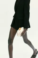 Bolso de mano tipo clutch con acabado nacarado y cierre de clip con detalle metálico dorado en la parte superior. Incluye cadena metálica para usar como bandolera.