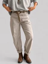Pantalón de corte recto y holgado en color beige, con cintura elástica y dobladillo en los tobillos. Incluye un cinturón de cuero sintético con tachas metálicas decorativas.
