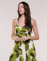 Vestido maxi de fondo blanco con estampado de flores grandes en tonos verde y marrón, con escote en V, breteles finos y detalle de abertura cut-out en el centro del busto.