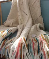 Chal de lana merino de gran tamaño, con diseño de texturas, rombos y calados, terminado con largos flecos multicolor.