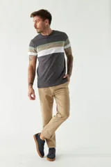 Pantalón chino color beige, de corte slim, con bolsillos laterales y traseros. Se ajusta a la cintura con cinturón de cuero marrón.