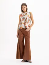 Blusa Pop de voile de seda y algodón, color blanco con estampado exclusivo de motivos frutales y florales. Presenta silueta en línea A, calce holgado, cuello alto fruncido con volados y escote profundo con volados caracol al frente.