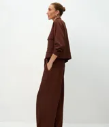 Pantalón de corte wide leg color marrón, con cintura alta, elástico posterior, bolsillos delanteros amplios y cinta con hebilla para lazo en la cintura.