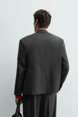 Blazer de corte regular confeccionada en tejido con lana, con diseño de botonadura cruzada. Presenta cuello con solapas de pico, manga larga con puños abotonados, bolsillos de solapa en la cadera y abertura central en la espalda.