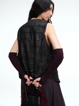 Chaleco sastrero de denim negro con diseño de cuadros y aplicación de lentejuelas sutiles. Presenta escote en V, cierre frontal con botones metálicos y bolsillos delanteros.