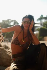 Collar con un gran dije en forma de caballo de color dorado, montado sobre un cordón de tiento de cuero marrón oscuro.