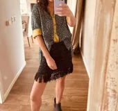 Minifalda negra tejida en lurex plateado, con flecos en el ruedo y cintura elástica.