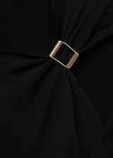 Chaleco de punto fino color negro, con cuello redondo y detalle metálico en el hombro. Diseño recto y sin mangas.