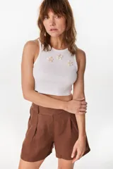 Musculosa blanca de algodón con diseño acanalado y detalles de apliques de flores formadas con caracoles en el frente.