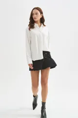 Camisa de viscosa blanca de corte holgado, con mangas largas, cuello camisero, cierre frontal con botones y detalle de bolsillo otonado en el pecho.