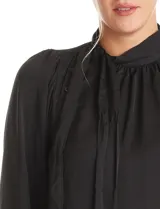 Blusa negra de acabado satinado con cuello alto fruncido, detalle de lazo para anudar y cierre lateral con botones. Presenta mangas largas estilo balloon con puños ajustados.