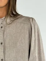 Camisa color beige con cuello mao, mangas largas abullonadas y cierre frontal con botones.