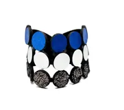 Pulsera ancha de cuero negro con tres filas de círculos de cuero en azul, blanco y negro con textura craquelada. Cierre a presión.