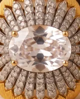 Anillo grande de bronce con baño de oro, diseño texturizado en forma de flor con incrustaciones de circón pavé y una piedra central ovalada transparente.