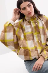 Campera bomber oversize de paño italiano con estampado en zigzag blanco y negro, cuello alto y cierre frontal con broches a presión. Tiene mangas murciélago.