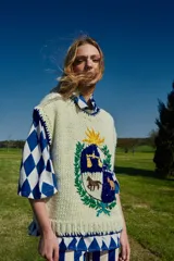 Chaleco de lana merino color crema, tejido y bordado a mano, con diseño de escudo con animales y sol.