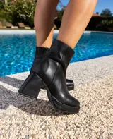 Botas cortas negras de cuero vacuno con textura tipo cocodrilo. Taco de madera forrado en cuero de 8cm, entre suela de goma de 2cm forrada en cuero, inclinación de horma de 6cm y caña de 15cm. Cierre YKK del lado interno y horma de punta cuadrada.