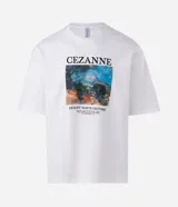 Remera boxy de algodón color blanco, con cuello redondo y mangas cortas. Presenta un estampado artístico inspirado en la obra "Mount Sainte-Victoire" de Paul Cézanne.