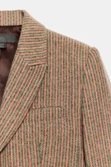 Blazer de corte clásico con cuello solapa y manga larga, confeccionado en tejido con patrón de espiga en tonos tierra y líneas verticales en color salmón. Cuenta con bolsillos delanteros y cierre frontal con botones ocultos.