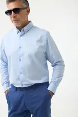 Camisa de vestir azul con cuello abotonado, corte clásico y mangas largas.