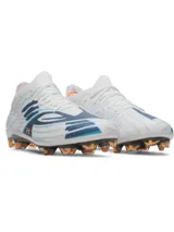 Championes de fútbol Under Armour Shadow Elite 4 Mach FG, color blanco con detalles en azul y naranja. Presentan una placa de fibra de carbono optimizada para mayor agilidad, microtextura háptica 3D en el empeine para un contacto óptimo con el balón y cuello elástico de punto para un ajuste ceñido.