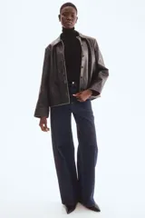 Polera negra de punto fino suave, con cuello alto, manga larga y bajo recto. Cuello, puños y bajo acanalados.