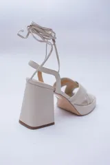 Sandalias color beige con plataforma y tacón cuadrado. Presentan tiras cruzadas en el empeine y tiras largas para atar alrededor del tobillo.