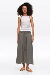 Falda midi de corte en línea A color negro con diseño de cuadros vichy blancos y negros, con bolsillos laterales y cintura elástica.